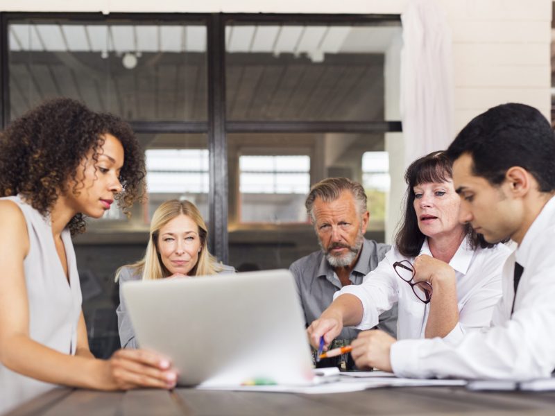 Business people using laptop at meeting in office